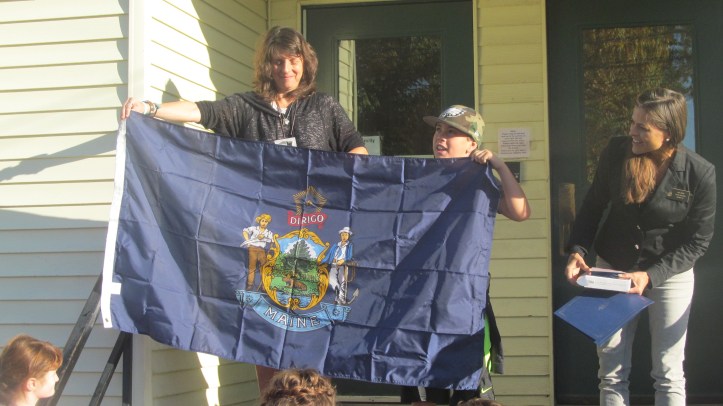 Sen Keim and student, Gabriel Damon, opening the flag